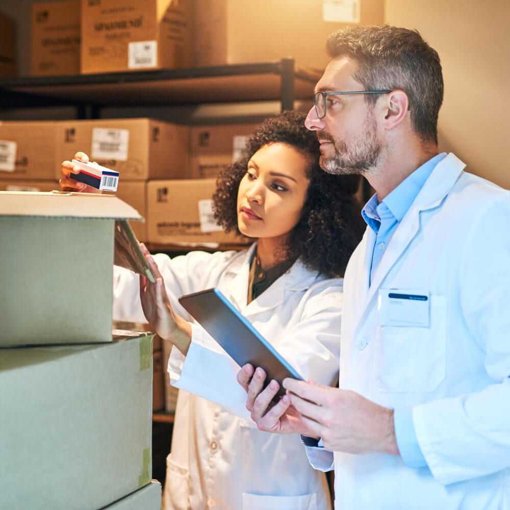 Two people in lab coats looking at boxes.