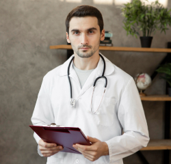 A male doctor holding a clipboard in his hands.